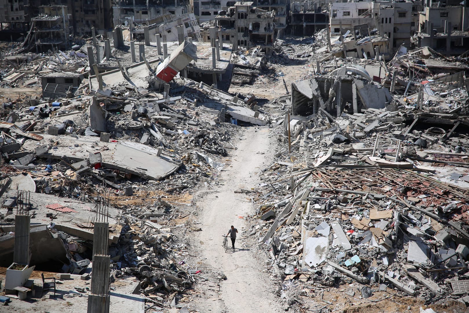 A man pushes a bycicle along as he walks amid building rubble in the devastated area around Gaza's Al-Shifa hospital on April 3, 2024, amid the ongoing conflict between Israel and Hamas. A steadily climbing death toll, reported by the Hamas-run territory's health ministry, nears 40,000 people killed in Gaza on August 5,2024 since war between Israel and Palestinian militants broke out on October 7, 2023. (Photo by AFP)